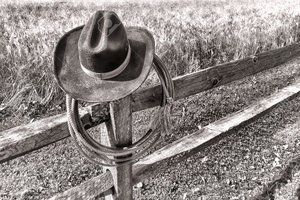 20786968-American-West-rodeo-traditional-cowboy-hat-and-roping-lasso-lariat-hanging-on-an-old-wood-fence-post-Stock-Photo.jpg