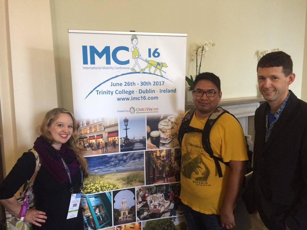From left to right: Tara Brown-Ogilvie, Garrison Tsinajinie, and Kevin McCormack, standing in front of the IMC16 banner.