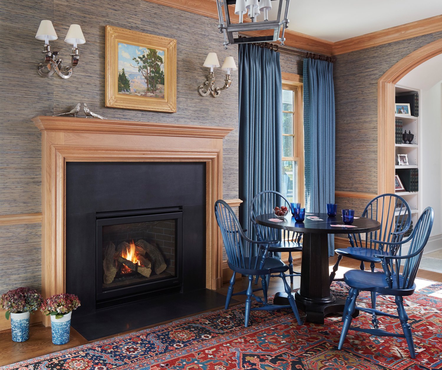 Blue windsor chairs near a cozy fireplace in a family room with grasscloth wall covering. Come see more interior design inspiration from Elizabeth Drake. Photo by Werner Straube. #interiordesign #classicdesign #traditionaldecor #housetour #elizabethdrake