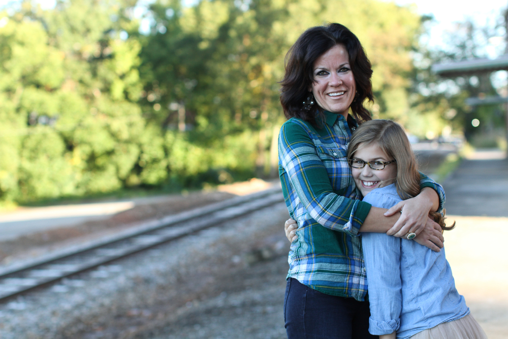 Mom and daughter hugging in front of railroad tracks