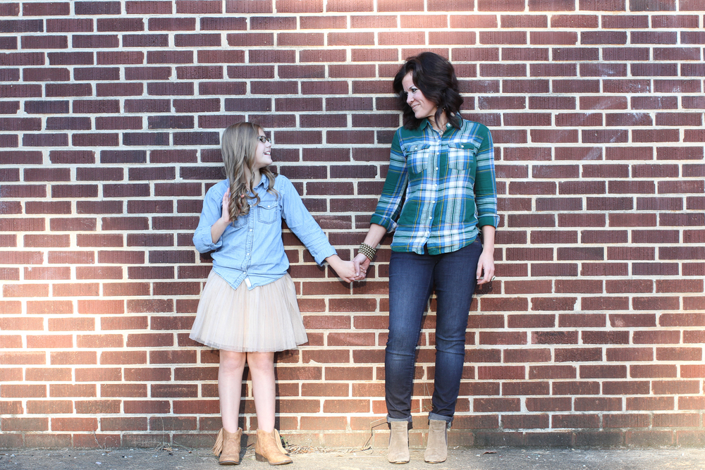 Mom and Daughter holding hands in front of brick wall