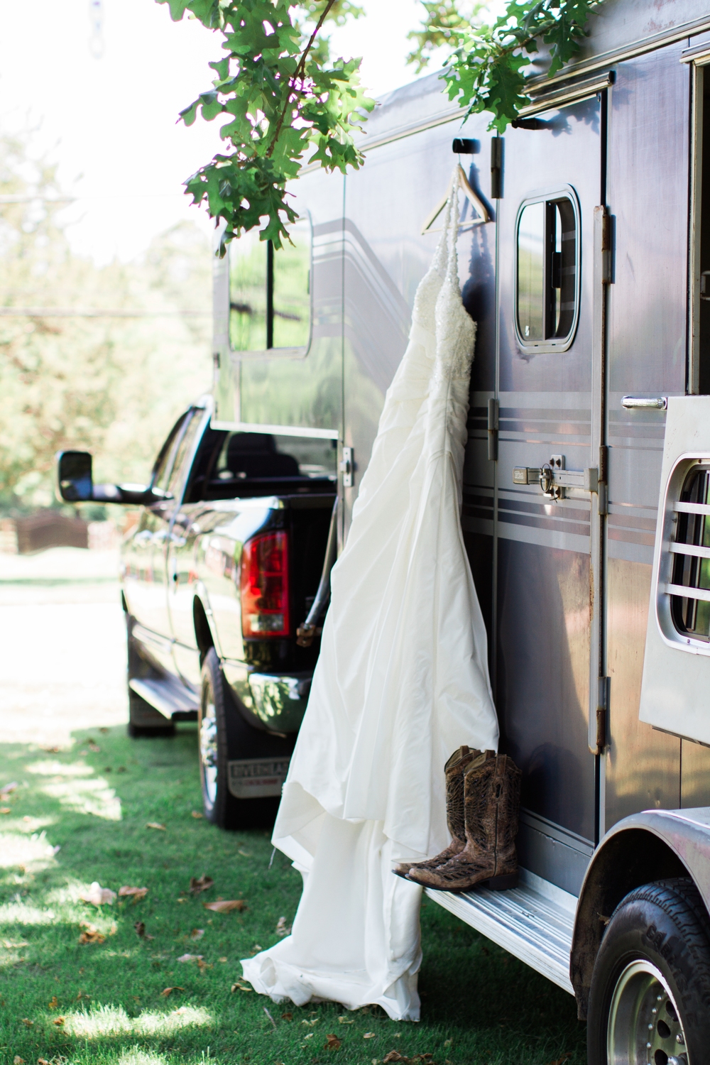 Brides dress hanging from Horse Trailer along with her cowboy boots.