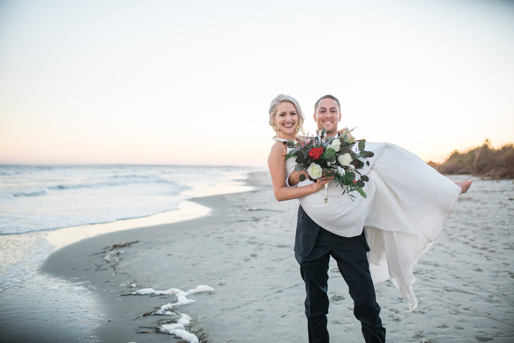 Groom holding bride at shore