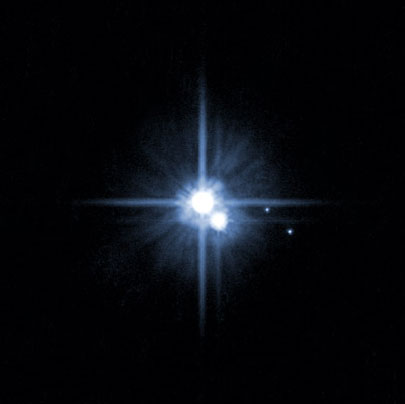 In 2005, this image from NASA's Hubble Space Telescope was used to identify two new moons orbiting Pluto. Pluto is in the center. The moon Charon is just below it. The newly discovered moons, Nix and Hydra, are to the right of Pluto and Charon. Image Credit: NASA, ESA, H. Weaver (JHU/APL), A. Stern (SwRI), and the HST
