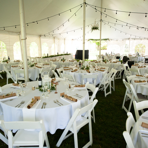  The inside of the reception tent set up with white linens, lanterns and bistro lights 