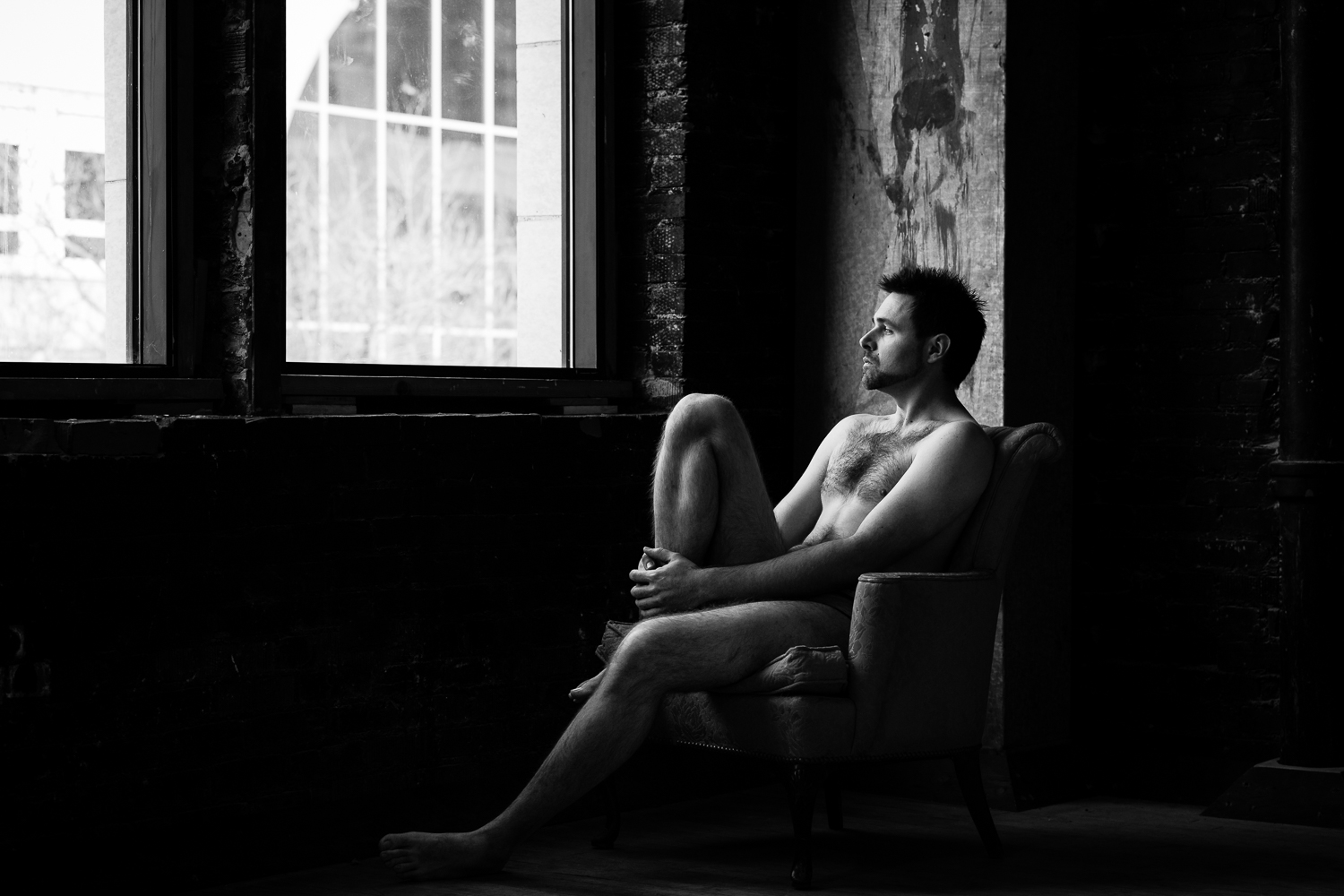 montana-male-boudoir-photoshoot-man-sitting-in-chair-looking-out-window.jpg
