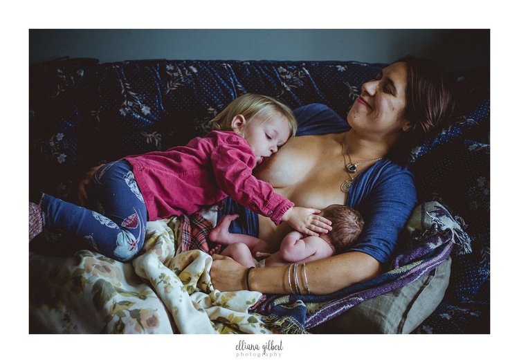 She looked down, and saw her daughter caressing her newborn, while nursing them both at the same time, and in that moment, her heart blew up tenfold, and she couldn't help but smile. Image by Elliana Gilbert Photography. 