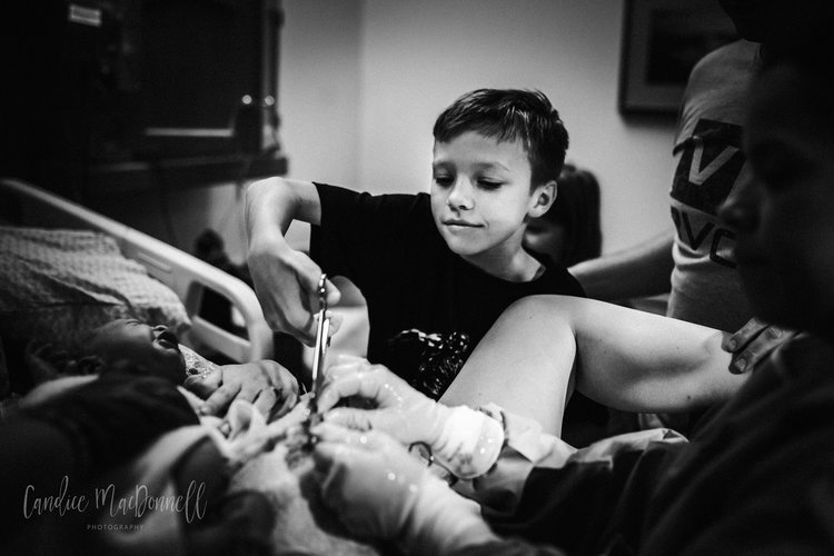 Older brother helps cut the cord. Lovely image by Candice MacDonnell Photography. 
