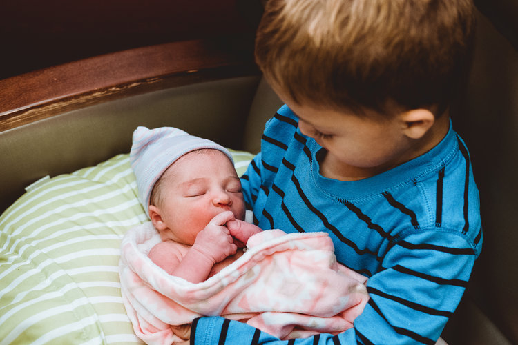 Big brother holds baby for the very first time. Image by Hilary Marie. 