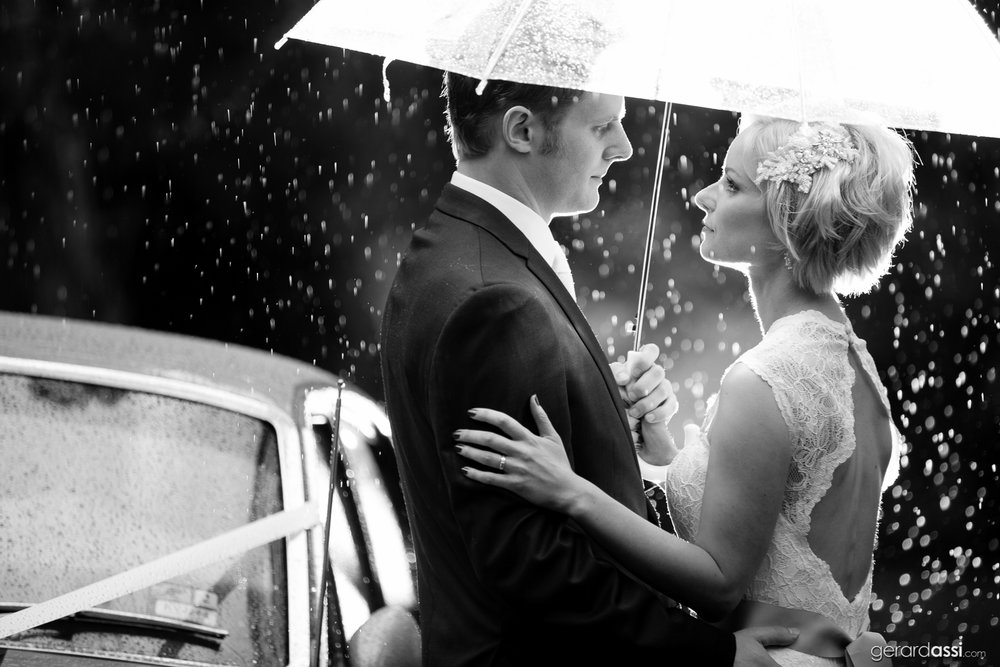 Bride and Groom looking into each others eyes under an umbrella at their rainy day wedding