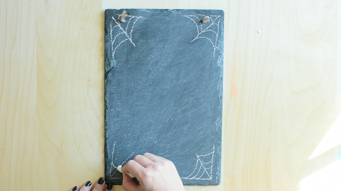 In all 4 corners of the chalkboard draw spider webs