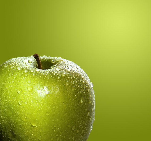 A green apple on a green background misted with water