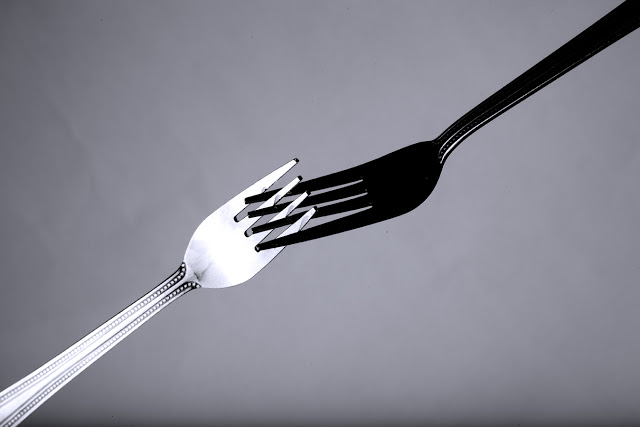 Two forks shot in a studio, one is black and one is white.