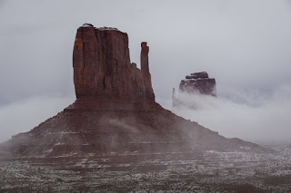 The West and East Mitten become visible as the fog clears after a mid December snow in Monument Valley, Ariz.