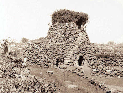 An agricultural watchtower photographed in the last century (ca. 1900-1920). Note the stair on the near side with a seated man near the top, the brush covered turret, and the arched doors leading into enclosed rooms beneath. Image from here.