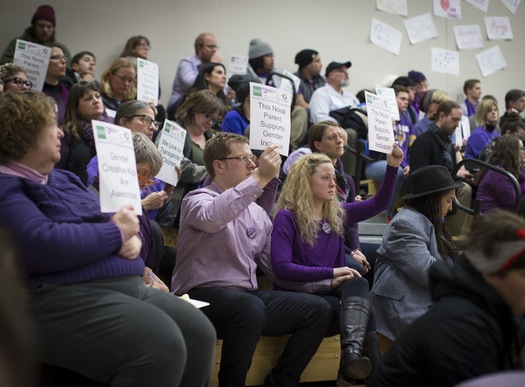Dave and Hannah Edwards (center, holding hands), parents of a gender-nonconforming child, sat in silent protest during Tuesday's presentation. Caption via the Star Tribune coverage, photo Renee Jones Schneider.