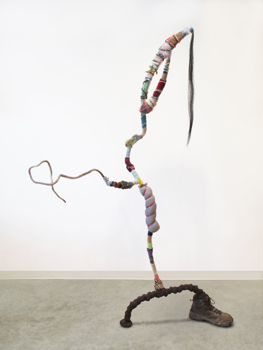  Gina Herrera, A Salutation to All , Assorted found materials, 77 x 50 x 19 inches "Reclaimed natural and man-made waste take on a humanoid shape, down to the wide-legged stance featuring an abandoned work boot. A twisting stick appendage extends in greeting, seeks acknowledgement." 