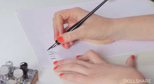 Bryn Chernoff demonstrates how to hold your nib pen at a 45-degree angle from the surface of the paper.
