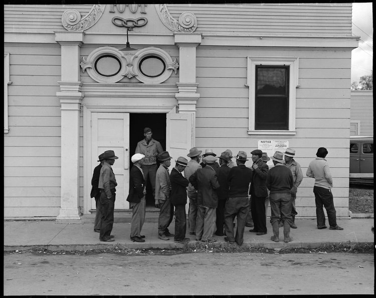 April 28, 1942 — Byron, California. Field laborers of Japanese ancestry from a large delta ranch have assembled at Wartime Civil Control Administration station to receive instructions for evacuation which is to be effective in three days under Civilian Exclusion Order Number 24. They are arguing together about whether or not they should return to the ranch to work for the remaining five days or whether they shall spend that time on their personal affairs.