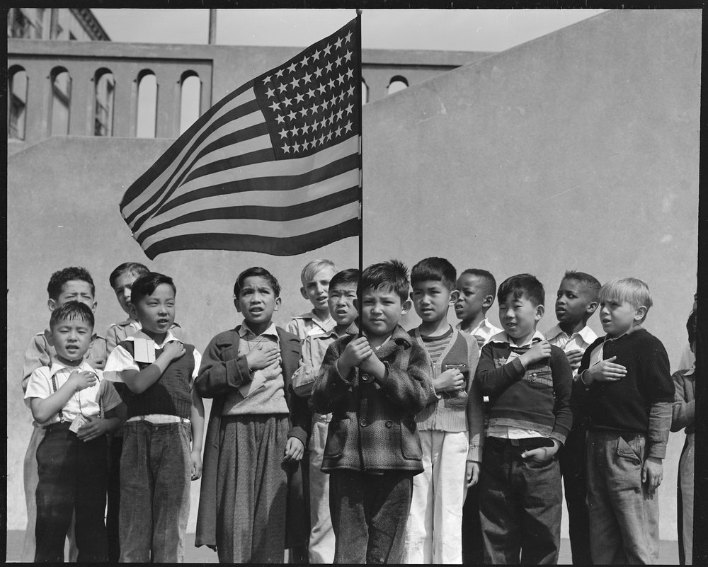 PRINT AVAILABLE April 20, 1942 — San Francisco, California. Flag of allegiance pledge at Raphael Weill Public School, Geary and Buchanan Streets. Children in families of Japanese ancestry were evacuated with their parents and will be housed for the duration in War Relocation Authority centers where facilities will be provided for them to continue their education.