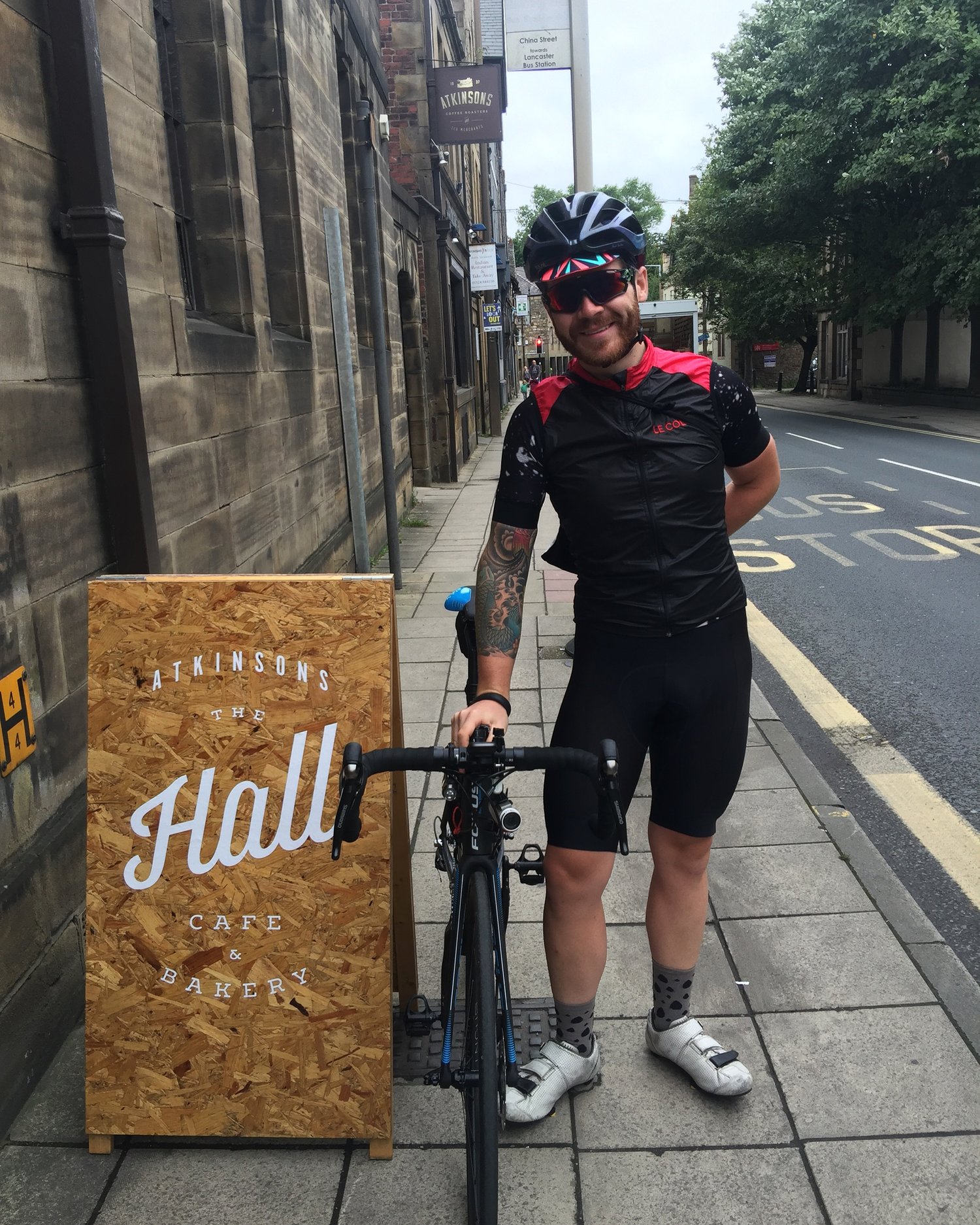 Chris Hall next to a sign that says 'The Hall Cafe'
