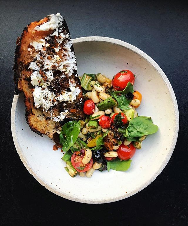 Cannelini beans, tomatoes, okra, and arugula pesto served with goat cheese toast dusted with dry mole 📷: @chefjosefcenteno
