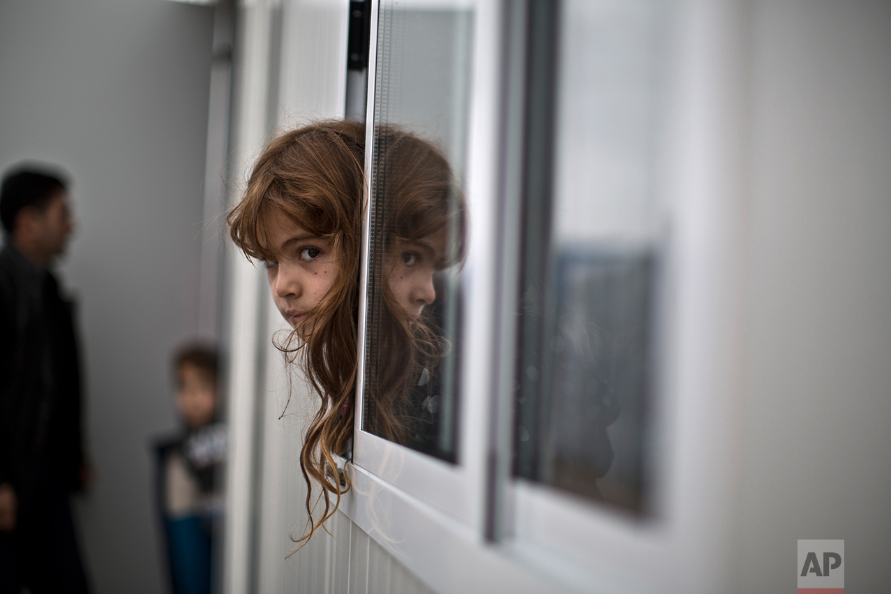 An Iraqi refugee girl looks outside her family's shelter at the refugee camp of Ritsona about 86 kilometers (53 miles) north of Athens, Wednesday, Dec. 28, 2016. (AP Photo/Muhammed Muheisen)
