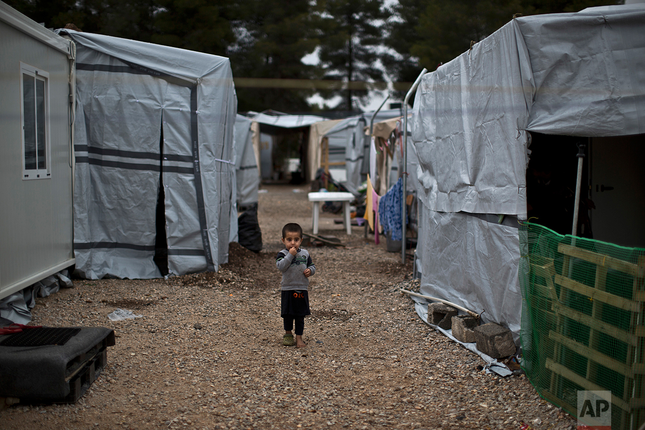 A Syrian refugee child walks between shelters at the refugee camp of Ritsona about 86 kilometers (53 miles) north of Athens, Wednesday, Dec. 28, 2016. (AP Photo/Muhammed Muheisen)