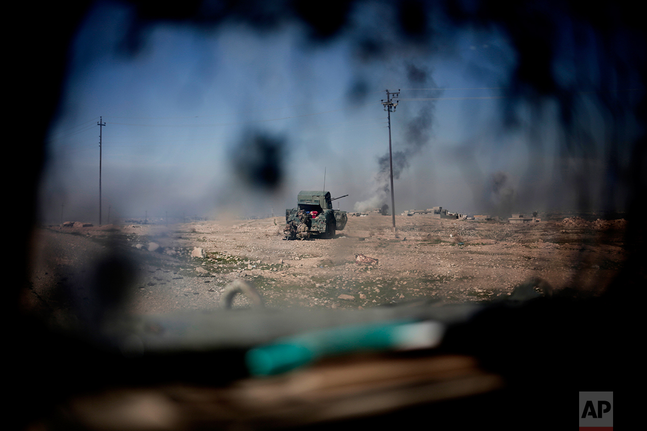 Iraqi police forces fire from a humvee at Islamic State positions from a hill side outside the town of Abu Saif, Monday, Feb. 20, 2017. (AP Photo/Bram Janssen)