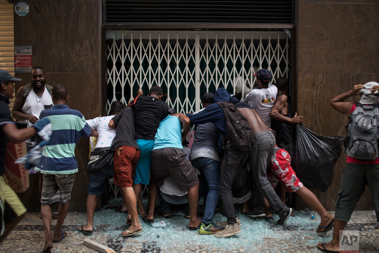 People break into a store during clashes with riot police at a protest against the state government in Rio de Janeiro, Brazil, Thursday, Feb. 9, 2017. The protesters are denouncing a proposal to privatize the state's water and sewage company. (AP Photo/Felipe Dana)