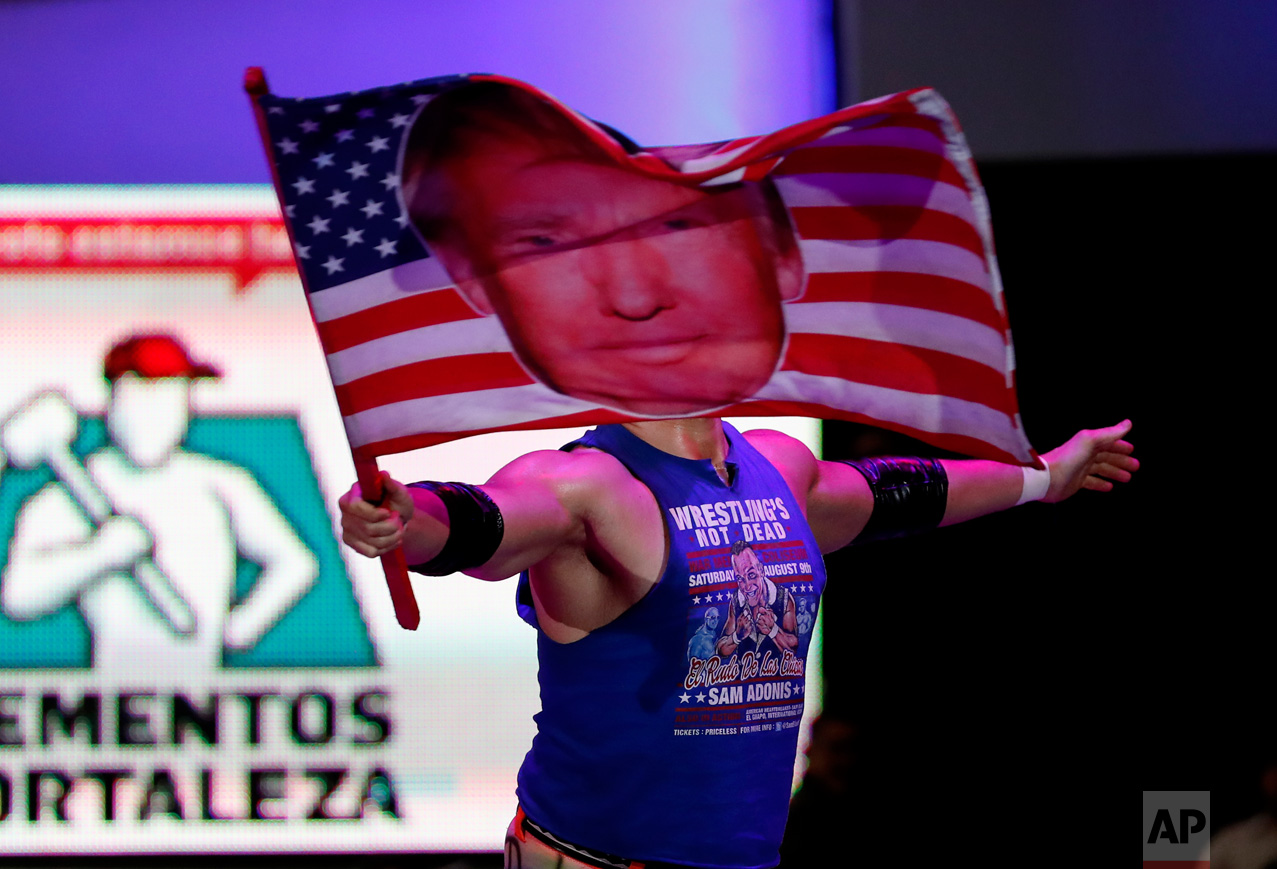 American pro wrestler Sam Polinsky aka Sam Adonis takes the ring at Arena Mexico waving an American flag emblazoned with a photo of U.S. President Donald Trump, in Mexico City, Sunday, Feb. 12, 2017. He's the guy Mexicans love to hate: The wrestler has become a sensation in Mexico City by adopting the ring persona of a flamboyant Trump supporter. (AP Photo/Eduardo Verdugo)
