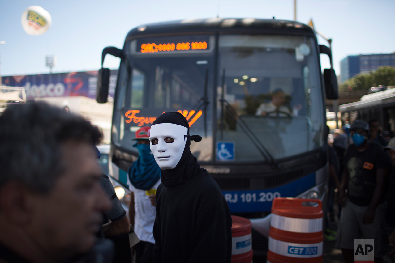 A masked demonstrator stands in front a bus as he blocks a street next to the Sambodrome during a protest against the state government in Rio de Janeiro, Brazil, Monday, Feb. 20, 2017. The protesters are denouncing a proposal to privatize the state's water and sewage company. (AP Photo/Leo Correa)
