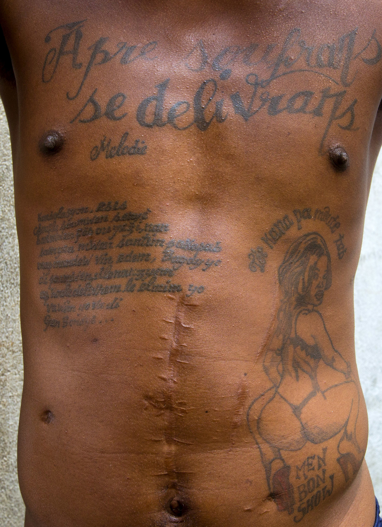 This Feb. 13, 2017 photo shows the tattoos on the chest and abdomen of a prisoner incarcerated at the National Penitentiary in downtown Port-au-Prince, Haiti. The tattoo on his chest reads in Haitian Creole: "After suffering is deliverance." ( AP Photo/Dieu Nalio Chery)