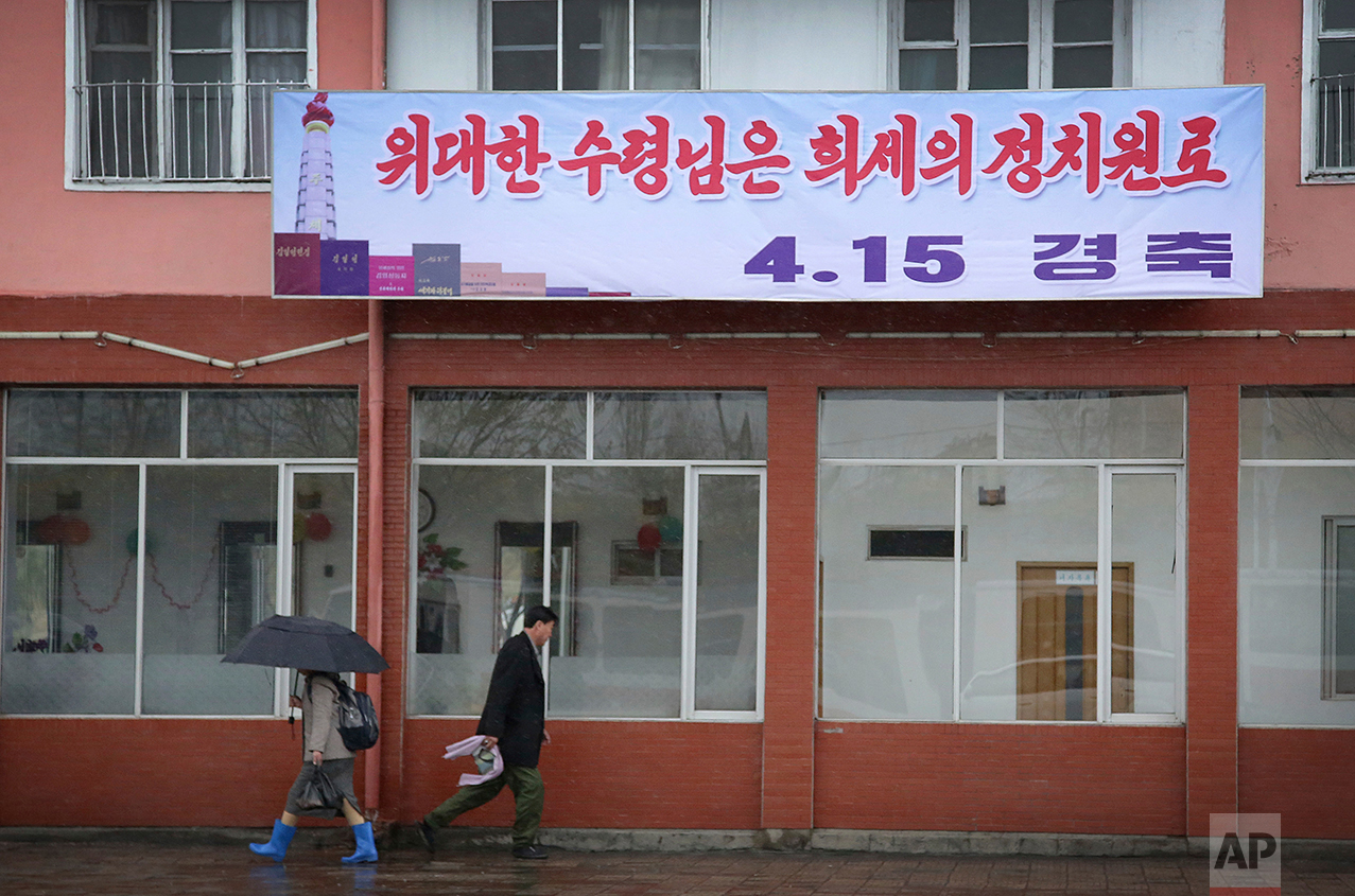 Pedestrians walk in the rain beneath a sign which reads "Great President, Extraordinary Political Veteran" referring to late leader Kim Il Sung on Friday, April 14, 2017, in Pyongyang, North Korea. (AP Photo/Wong Maye-E)