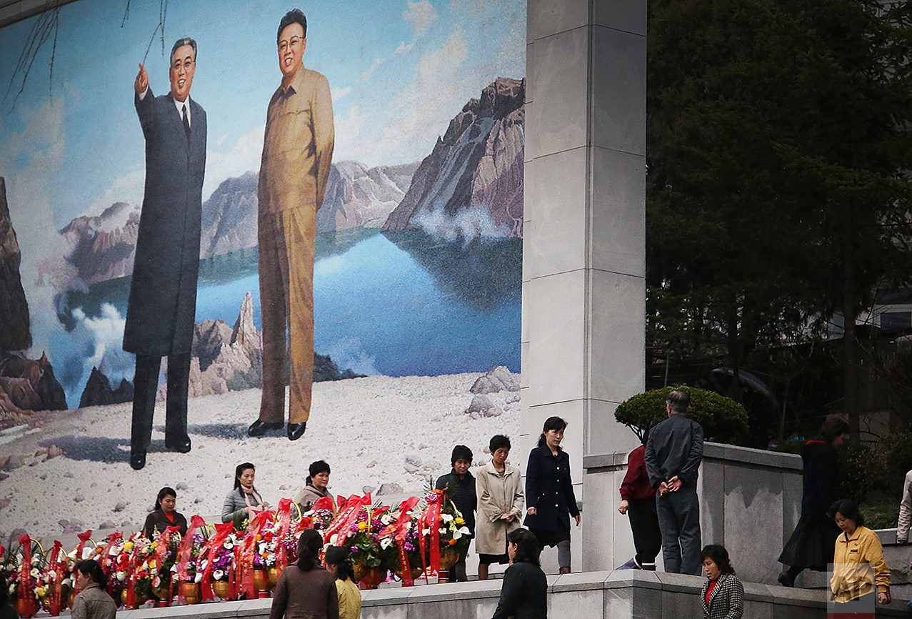 North Koreans offer flowers in front of a mural of late leaders Kim Il Sung, left, and Kim Jong Il on Friday, April 14, 2017, in Pyongyang, North Korea. (AP Photo/Wong Maye-E)