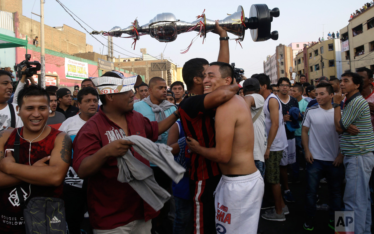  In this Monday, May 1, 2017 photo, a fan of the "Purito Barrios Altos" soccer team holds high his team's trophy as he hugs a player after the Little World Cup of Provenir street soccer championship in Lima, Peru. The team clenched the championship after a day of 30 back-to-back games. (AP Photo/Martin Mejia) 