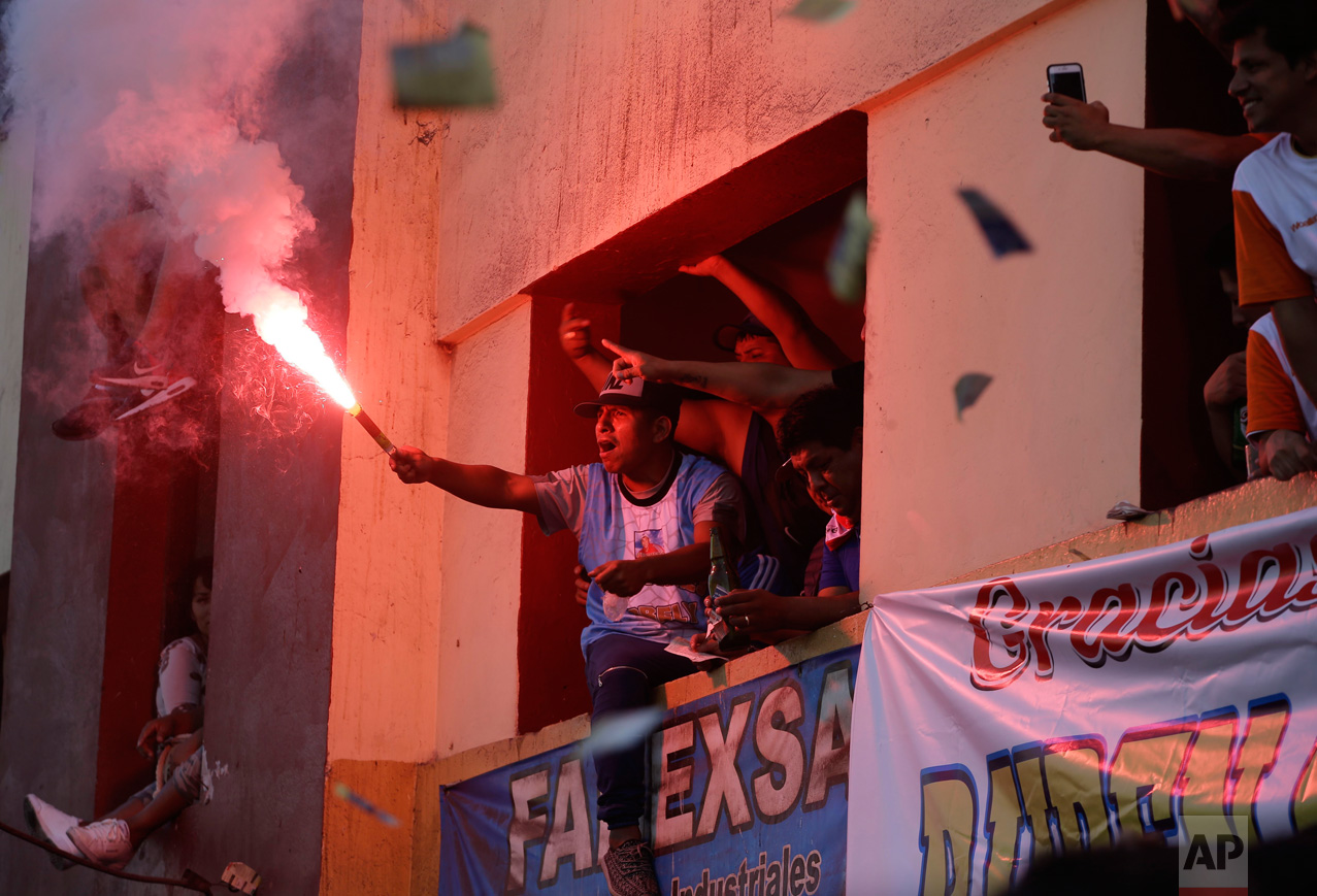  In this Monday, May 1, 2017 photo, a soccer fan lights a flare from an apartment building balcony overlooking the Little World Cup Porvenir street soccer championship in Lima, Peru. The working-class neighborhood ritual in El Porvenir began in the 1950s as a challenge to the Manuel Odria military dictatorship when playing in the streets was forbidden. (AP Photo/Martin Mejia) 