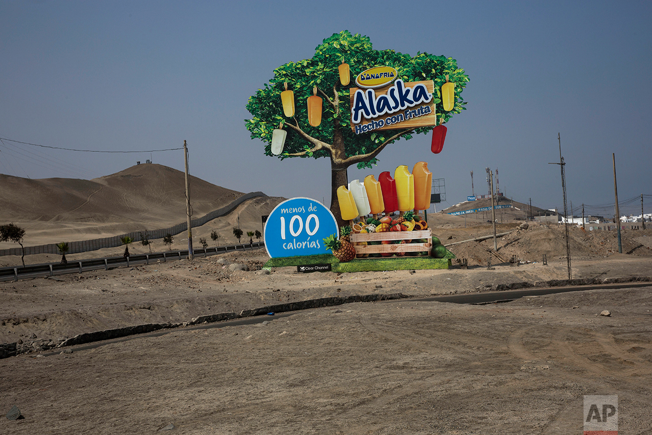 In this May 5, 2017 photo, a billboard advertising popsicles stands along the Pan American Highway on the south side of Lima, Peru, Friday, May 5, 2017. In the coastal regions, home to the capital Lima and most of the country's industry, the 2014 poverty rate was 14.3 percent, according to government statistics. (AP Photo/Rodrigo Abd)