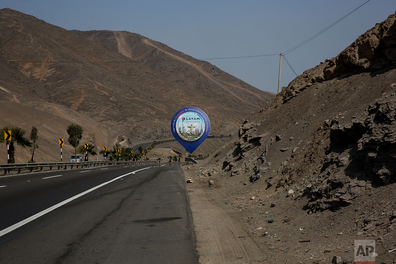 In this May 5, 2017 photo, a billboard advertising an airline stands along the Pan American Highway on the south side of Lima, Peru. The billboards advertise products the people living in this area are unlikely to be able to buy or afford. (AP Photo/Rodrigo Abd)
