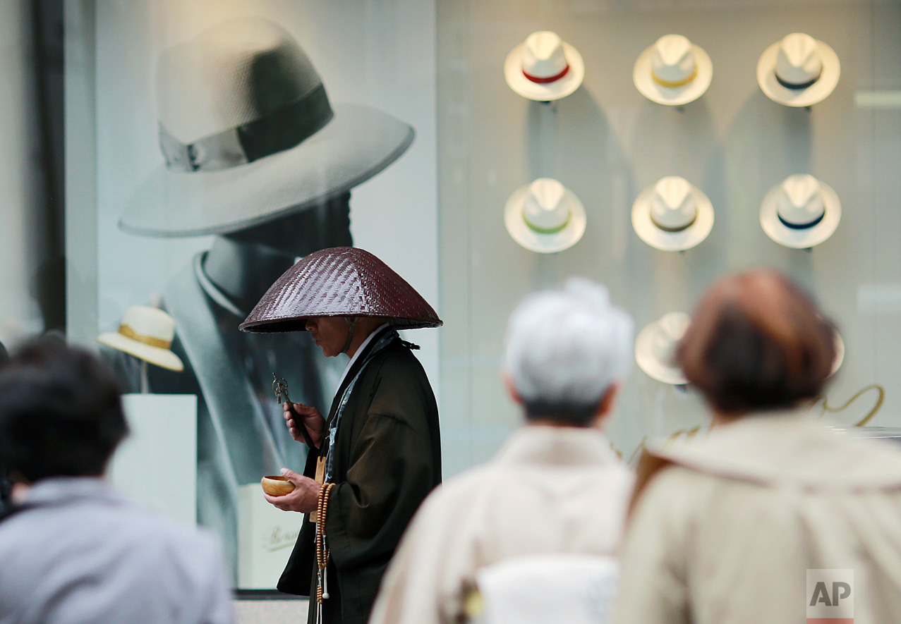 A Buddhist monk offers prayers in front of a window display of hats at a department store in the Ginza shopping district in Tokyo Tuesday, May 16, 2017. (AP Photo/Eugene Hoshiko)