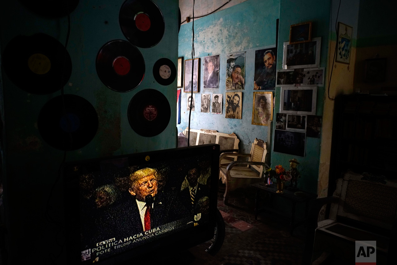 A television set shows U.S. President Donald Trump announcing his new Cuba policy, in a living room decorated with images of Cuban leaders at a house in Havana, Cuba, Friday, June 16, 2017. Trump declared he was restoring some travel and economic restrictions on Cuba that were lifted as part of Barack Obama's historic easing. (AP Photo/Ramon Espinosa)
