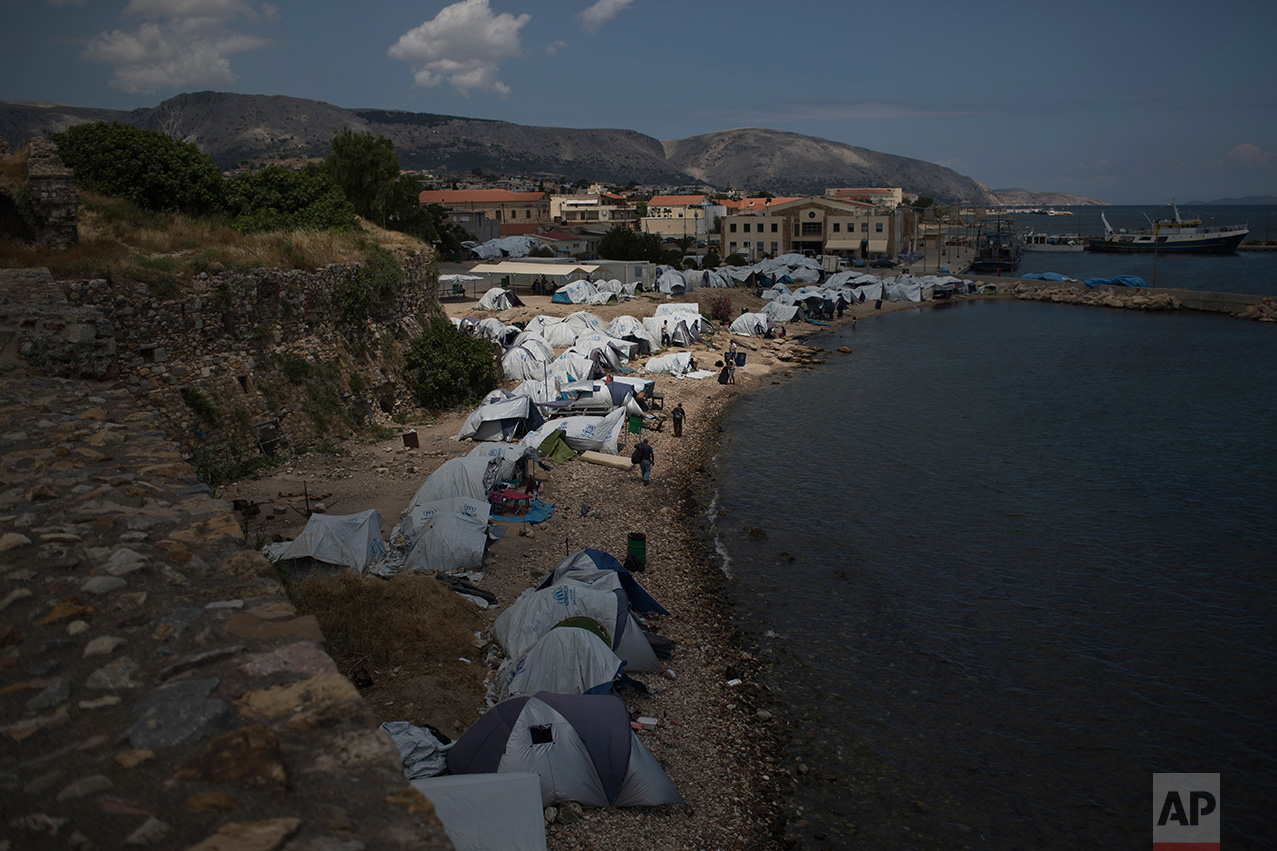 In this June 9, 2017 photo, tents that refugees and other migrants use as a temporary shelter stand on a beach near the Souda refugee camp, next to the medieval castle of Chios island, Greece.  (AP Photo/Petros Giannakouris)