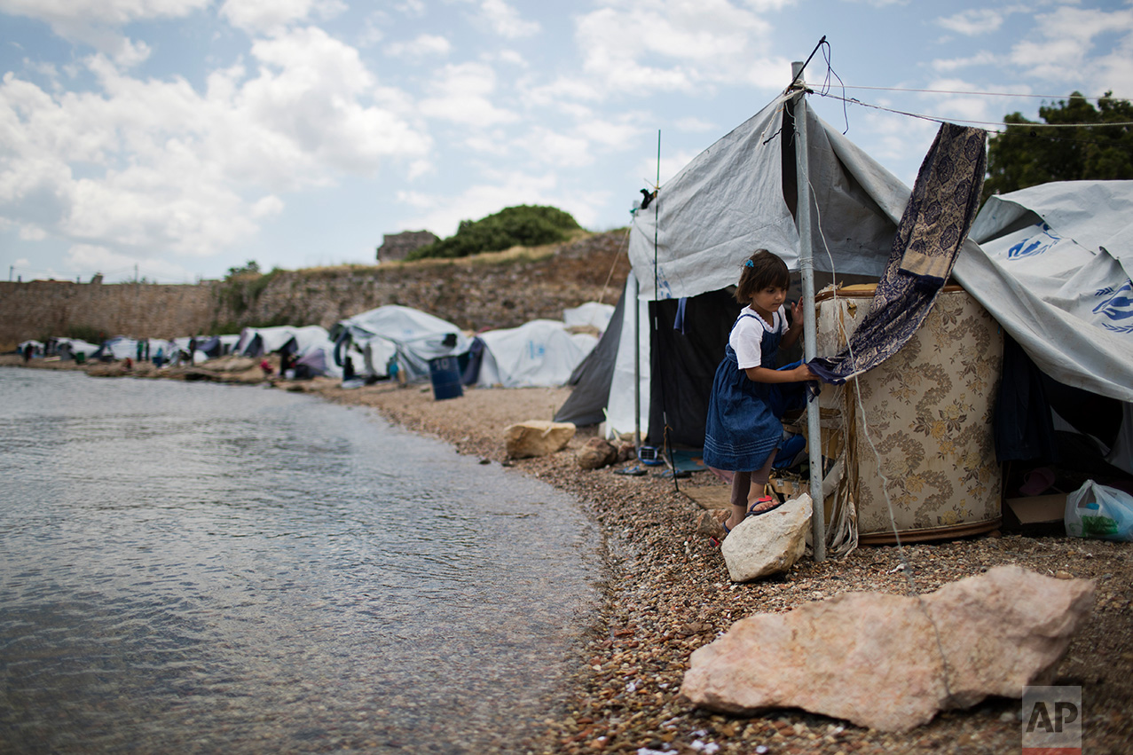 In this June 9, 2017 photo, a little girl from Syria walks on a beach where refugees and other migrants live in makeshift tents near the Souda refugee camp, under the medieval castle of Chios on Chios island, Greece. (AP Photo/Petros Giannakouris)
