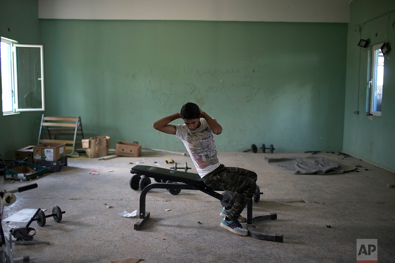 In this May 26, 2017 photo, 16-year- old Amor Biro from Syria works out at the refugee camp of Ritsona about 86 kilometers (53 miles) north of Athens. Amor and his family wants to go to Germany. (AP Photo/Petros Giannakouris)
