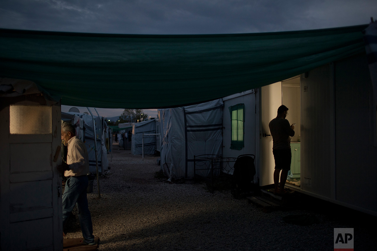 In this May 25, 2017 photo, refugees enter their shelters at the refugee camp of Ritsona about 86 kilometers (53 miles) north of Athens. (AP Photo/Petros Giannakouris)