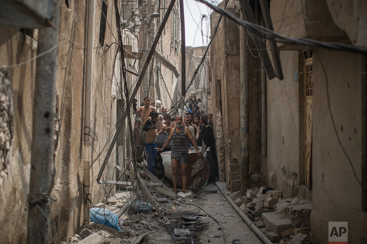 Civilians trying to flee get undressed to be checked for explosives after suicide bombers exploded as Iraqi forces continue their advance against Islamic State militants in the Old City of Mosul, Iraq, Monday, July 3, 2017. (AP Photo/Felipe Dana)