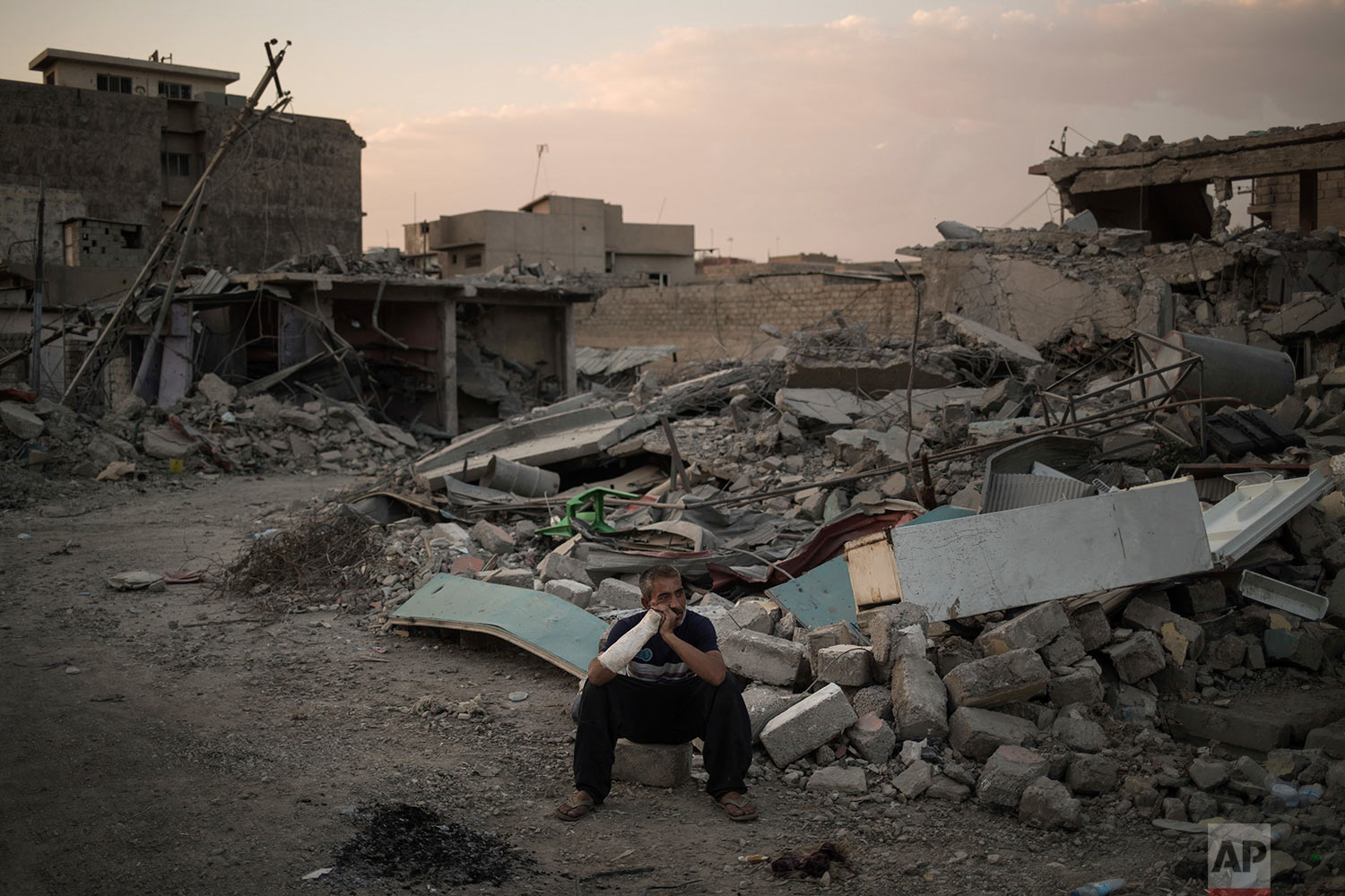 In this July 13, 2017 photo, Saddam Salih Ahmed, who was injured when his house was hit by an explosion, sits on his damaged street in the west side of Mosul, Iraq. (AP Photo/Felipe Dana)