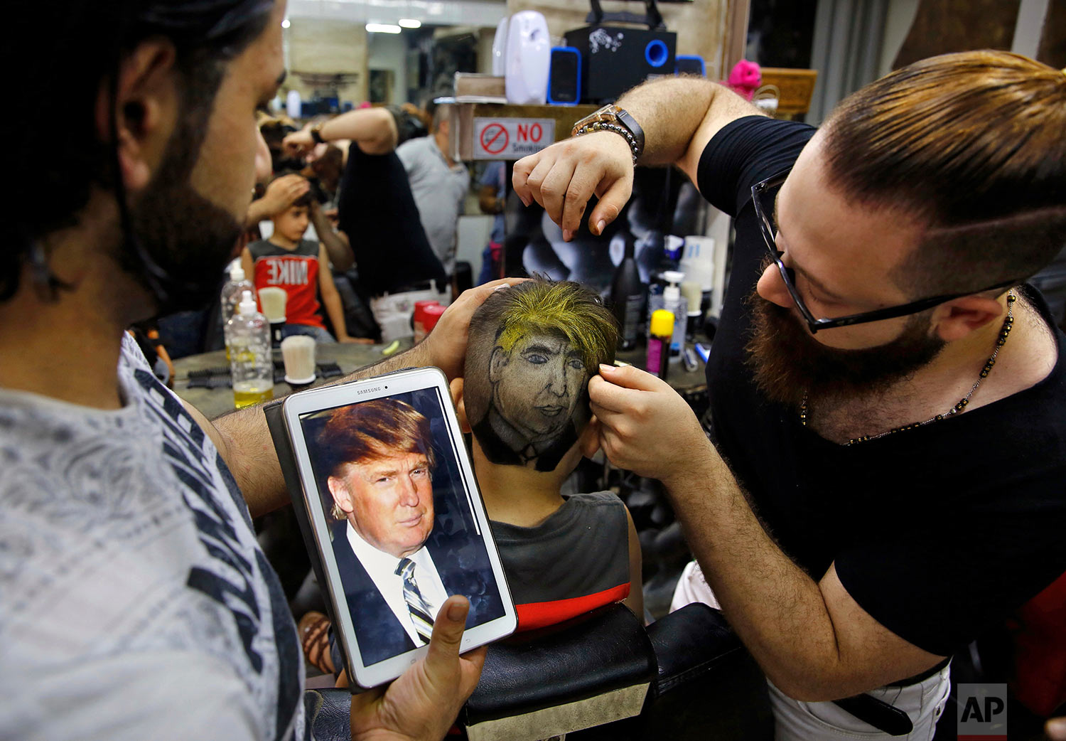 Muhannad Khaled Omar, right, prepares an image of U.S. President Donald Trump on the back of a customer's head at his barber shop in Burj al-Barajneh, southern Beirut, Lebanon on July 14, 2017. (AP Photo/Bilal Hussein)