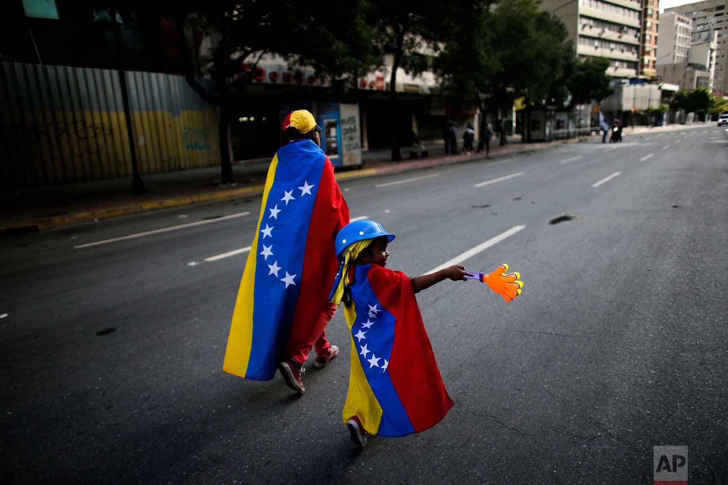 An anti-government demonstrator and her daughter wrapped in the Venezuelan flag walk on an empty street in Caracas, Venezuela, Sunday, July 30, 2017. (AP Photo/Ariana Cubillos)