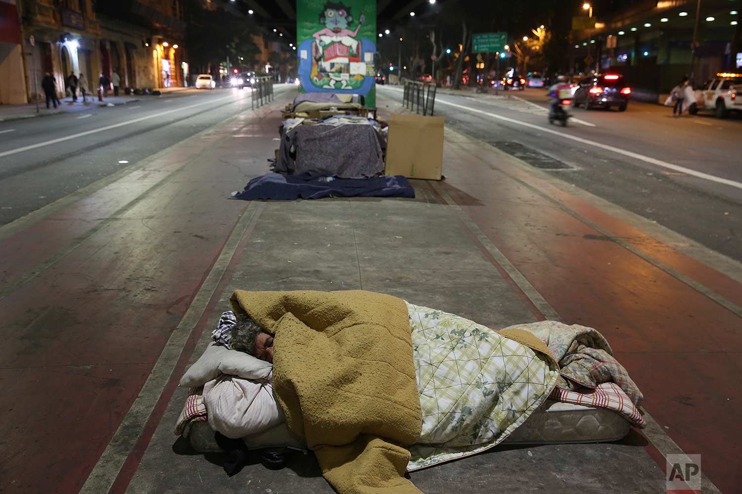 A homeless person sleeps on the sidewalk during a cold night in downtown Sao Paulo, Brazil, Wednesday, July 19, 2017. (AP Photo/Andre Penner)